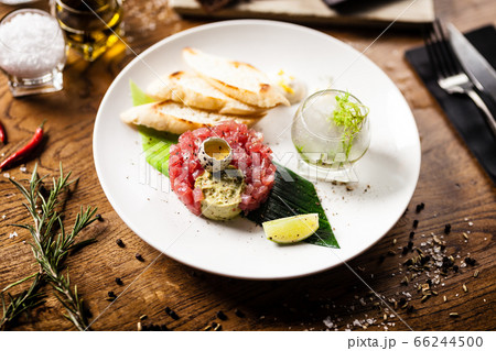 Tuna tartare: Guacamole quail egg baguette on a plate. Delicious healthy raw food closeup served for lunch on a table in modern gourmet cuisine restaurant Tuna tartare: Guacamole quail egg baguette on a plate. Delicious healthy raw food closeup served for lunch on a table in modern gourmet cuisine restaurant 66244500