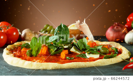 Falling raw ingredients on pizza 66244572