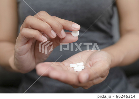 Close up of working woman taking in pill she is pours the pills out of the bottle,taking painkiller to reduce sharp ache concept,health care and medicine concept. Close up of working woman taking in pill she is pours the pills out of the bottle,taking painkiller to reduce sharp ache concept,health care and medicine concept. 66246214