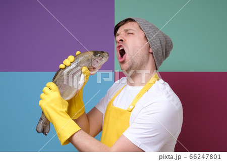 Fisherman in gloves and apron singing with fish. Fisherman in gloves and apron singing with fish. 66247801
