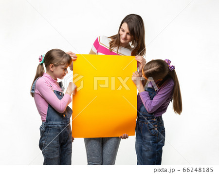 Mom and two daughters hold an orange sign in their Mom and two daughters hold an orange sign in their 66248185
