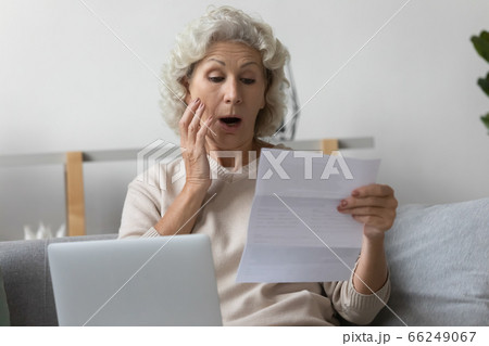 Shocked mature woman frustrated by unexpected news in letter correspondence Shocked mature woman frustrated by unexpected news in letter correspondence 66249067
