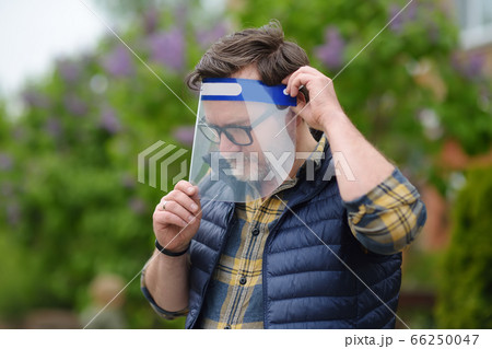 Man putting on face shield on street of city  66250047
