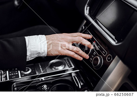 Businessman changing radio station while driving automobile Businessman changing radio station while driving automobile 66250607
