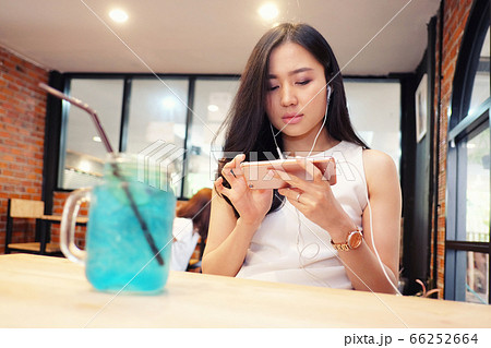 Young woman listening to music in coffee shop Young woman listening to music in coffee shop 66252664