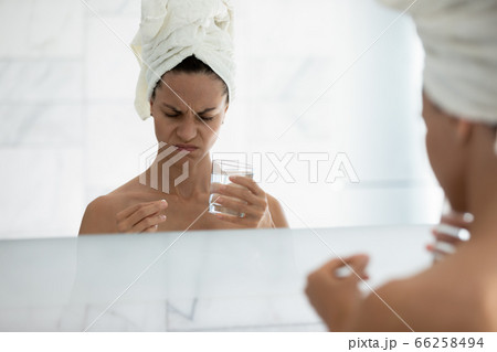 Mirror reflection unhealthy woman holding pill and glass of water Mirror reflection unhealthy woman holding pill and glass of water 66258494