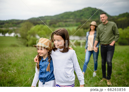 Happy family with two small daughters walking outdoors in spring nature. Happy family with two small daughters walking outdoors in spring nature. 66263856