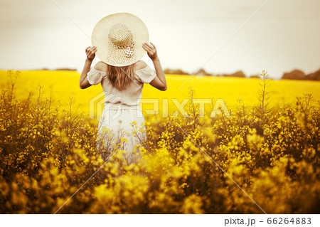 Young woman standing on the rape field with sunrise on the background 66264883