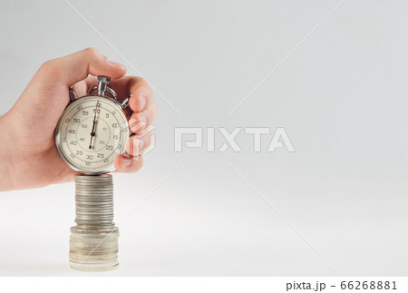 time is money. hand holding a stopwatch on a stack 66268881