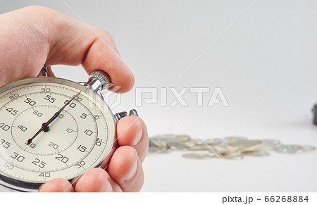 time is money. hand holding a stopwatch on a time is money. hand holding a stopwatch on a 66268884