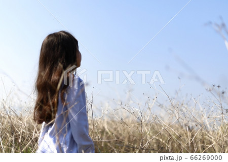 草むらで遠くを見つめる少女 66269000