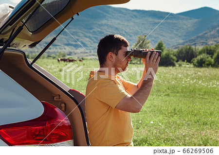 Young man at mountain looking through binoculars Young man at mountain looking through binoculars 66269506