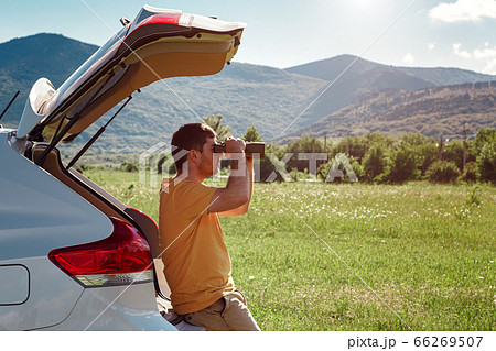 Young man at mountain looking through binoculars Young man at mountain looking through binoculars 66269507