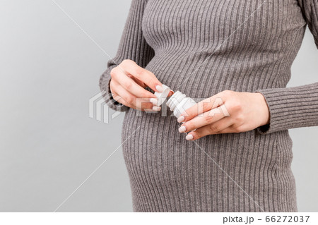 Close up of pregnant woman opening a bottle of Close up of pregnant woman opening a bottle of 66272037