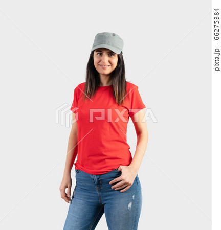 Young girl wearing blank red t-shirt, cap and blue jeans. Grey wall background Young girl wearing blank red t-shirt, cap and blue jeans. Grey wall background 66275384