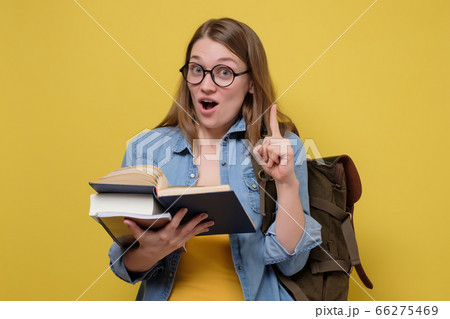 Attractive young female college student carrying a stack of books. Attractive young female college student carrying a stack of books. 66275469