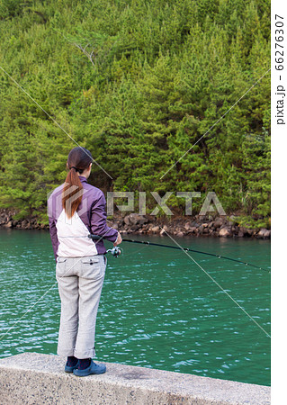 海で一人で釣りをする女性の後ろ姿 防波堤で浮き釣りをする女性の写真素材