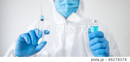 Doctor in PPE suit injecting vaccine 66278378