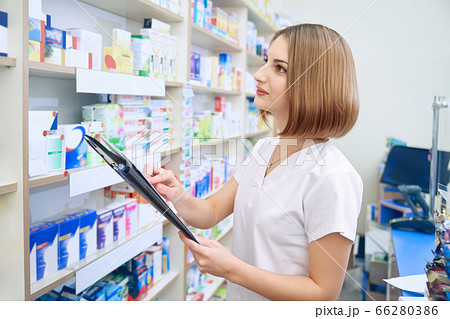 Female pharmacist with folder examinating medicaments. 66280386