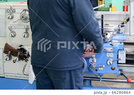 A male worker works on a larger metal iron A male worker works on a larger metal iron 66280864