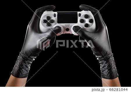 Hand in black gloves holding console gamepad isolated on black background 66281044