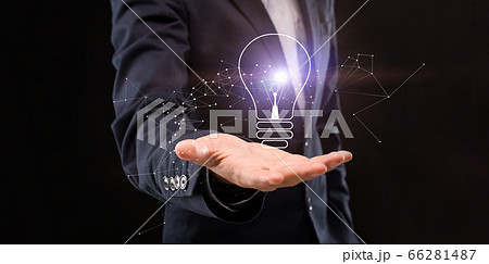 Businessman holding glowing lamp on black background Businessman holding glowing lamp on black background 66281487