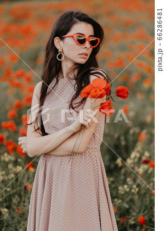 Girl posing in poppy field with red glasses Girl posing in poppy field with red glasses 66286481