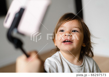 Toddler girl using phone with selfie stick to call grandparents. Virtual connection of people 66297573