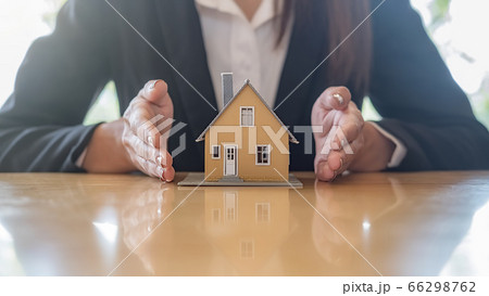 Agent hand protecting house model that shows to customers to get house insurance. Agent hand protecting house model that shows to customers to get house insurance. 66298762