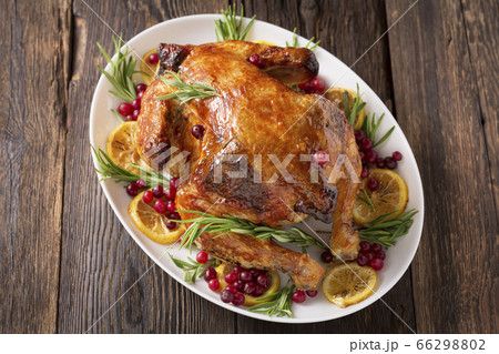 Thanksgiving Day traditional dish baked turkey. Roasted turkey or chicken with orange slices in plate for Christmas dinner on dark rustic background, top view, close up Thanksgiving Day traditional dish baked turkey. Roasted turkey or chicken with orange slices in plate for Christmas dinner on dark rustic background, top view, close up 66298802