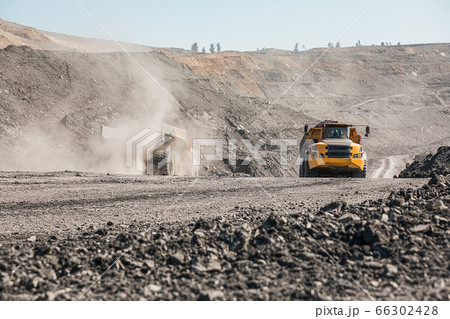 Large quarry dump truck. Loading the rock in dumper. Loading coal into body truck. Production useful minerals. Mining truck mining machinery, to transport coal from open-pit excavator work Large quarry dump truck. Loading the rock in dumper. Loading coal into body truck. Production useful minerals. Mining truck mining machinery, to transport coal from open-pit excavator work 66302428