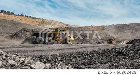 Large quarry dump truck. Loading the rock in dumper. Loading coal into body truck. Production useful minerals. Mining truck mining machinery, to transport coal from open-pit excavator work 66302429