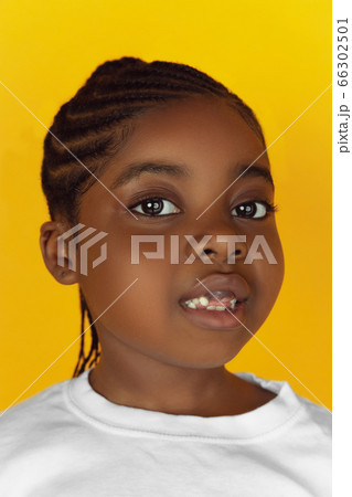 Little african-american girl's portrait isolated on yellow studio background Little african-american girl's portrait isolated on yellow studio background 66302501