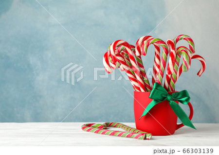 Candy canes in red cup on white wooden background, 66303139