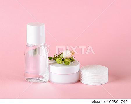 Skin tonic lotion or micellar water, facial cream, cotton pads and small rose on a pastel pink. 66304745