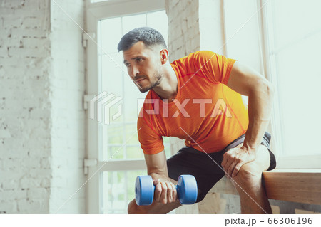 Young caucasian man training at home during quarantine of coronavirus outbreak, doing exercises of fitness, aerobic. Staying sportive during insulation. Young caucasian man training at home during quarantine of coronavirus outbreak, doing exercises of fitness, aerobic. Staying sportive during insulation. 66306196