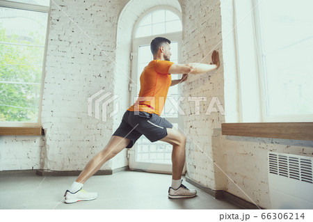 Young caucasian man training at home during quarantine of coronavirus outbreak, doing exercises of fitness, aerobic. Staying sportive during insulation. Young caucasian man training at home during quarantine of coronavirus outbreak, doing exercises of fitness, aerobic. Staying sportive during insulation. 66306214