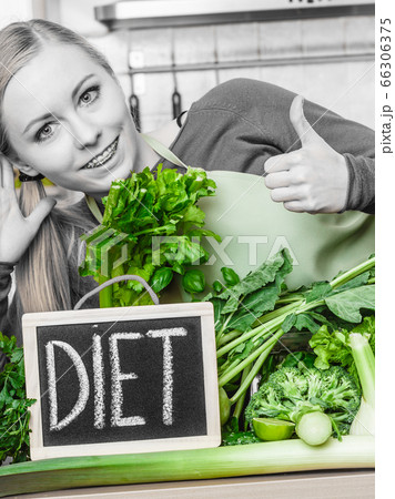 Woman in kitchen having green diet vegetables 66306375