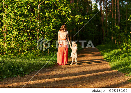 mother and little daughter walk along a path in a 66313162