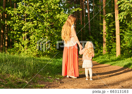 mother and little daughter walk along a path in a mother and little daughter walk along a path in a 66313163