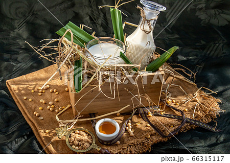 Soy products : A glass of Homemade soy milk and grains (soybeans) in wooden tray Served with brown sugar and honey with lighting in the morning. Soy products : A glass of Homemade soy milk and grains (soybeans) in wooden tray Served with brown sugar and honey with lighting in the morning. 66315117