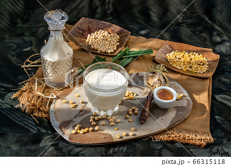 Soy products : A glass of Homemade soy milk and grains (soybeans) in wooden tray Served with brown sugar and honey with lighting in the morning. Soy products : A glass of Homemade soy milk and grains (soybeans) in wooden tray Served with brown sugar and honey with lighting in the morning. 66315118