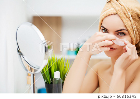 Young attractive woman with patches under eyes looking to the mirror Young attractive woman with patches under eyes looking to the mirror 66316345