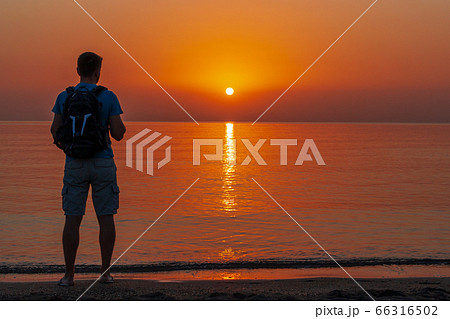 A man with a backpack stands on the beach and A man with a backpack stands on the beach and 66316502