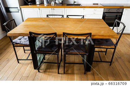 A big wooden dining table with metal wicker chairs in modern scandinavian an eat-in kitchen A big wooden dining table with metal wicker chairs in modern scandinavian an eat-in kitchen 66316709
