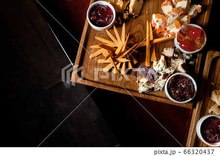 Wooden plate with various cheeses and jam 66320437