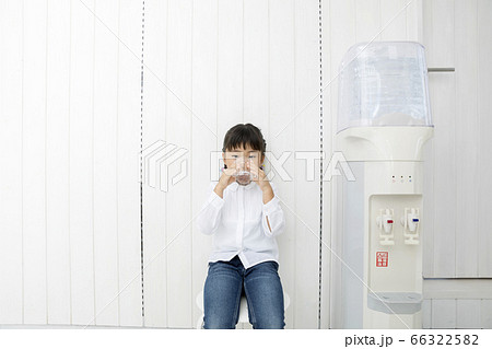 ウォーターサーバーの横で水を飲む子供 66322582