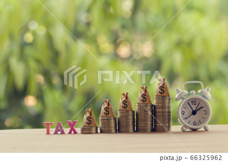 Finance tax concept: Words tax, alarm clock, US money bags on rows of rising coins. depicts ad valorem tax on value of a property Finance tax concept: Words tax, alarm clock, US money bags on rows of rising coins. depicts ad valorem tax on value of a property 66325962