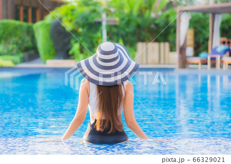 asian woman relax around outdoor swimming pool in hotel resort with palm tree at sunset or sunrise asian woman relax around outdoor swimming pool in hotel resort with palm tree at sunset or sunrise 66329021