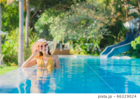 asian woman relax around outdoor swimming pool in hotel resort with palm tree at sunset or sunrise 66329024